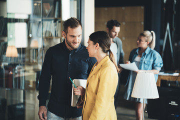 A walking meeting in the office. Man and woman employees talking about daily tasks