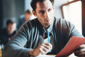 Handsome man employee sitting at the table and working with notepad