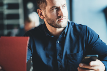 Handsome man employee sitting at the table and working with notepad and mobile phone