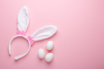 White rabbit bunny ears and eggs on pink background. Symbol Happy Easter Flat lay