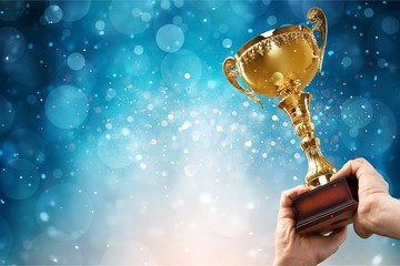 Hands holding golden trophy on a light background