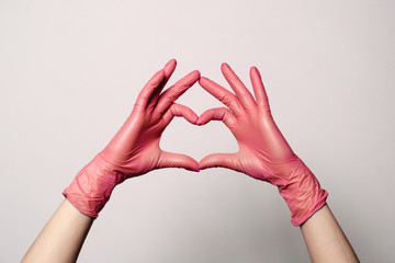 Closeup of a hand in latex rubber medical pink gloves folded into a heart sign. Isolated on white background. Concept love couple couple valentine - Powered by Adobe