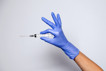 Closeup doctor's hand in rubber purple glove holding transparent syringe with closed cap. Isolated...
