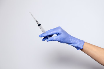 Closeup doctor's hand in rubber purple glove holding transparent syringe with closed cap. Isolated...