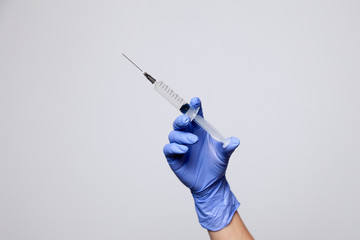 Closeup hand in rubber latex medicine purple glove holding transparent syringe with a sharp needle....