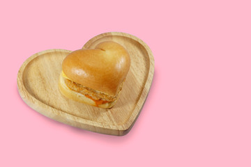 Heart shaped hamburger on wooden plate isoated on white background.