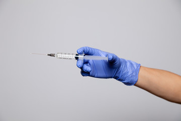 Closeup hand in rubber latex medicine purple glove holding transparent syringe with a sharp needle....
