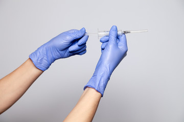Closeup doctor or nurse hands in rubber latex medical purple gloves holding a transparent syringe...