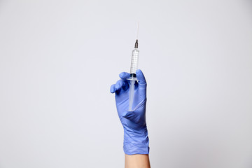 Closeup hand in rubber latex medicine purple glove holding transparent syringe with a sharp needle....