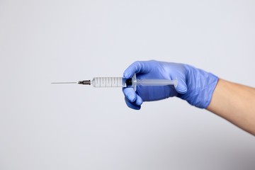Closeup doctor hand in rubber latex medical purple glove hold transparent syringe with sharp...
