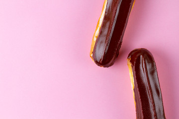 Traditional french dessert. Delicious eclairs with custard and chocolate icing on pink background....