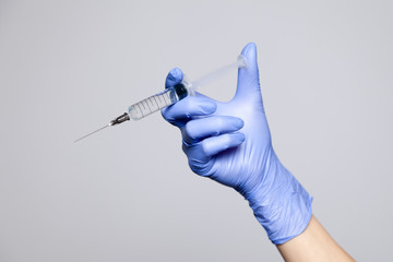 Closeup doctor hand in rubber latex medical purple glove hold transparent syringe with sharp...