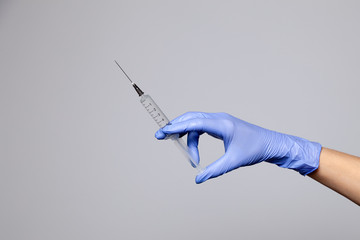 Closeup doctor's hand in rubber latex purple glove hold transparent syringe. Isolated on white...