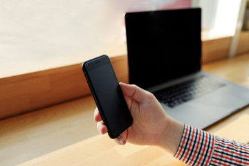 Male hand using laptop computer and smart phone.