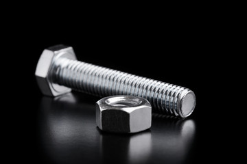 Steel fasteners of their bolts and nuts. Bolt and nut on a black background.