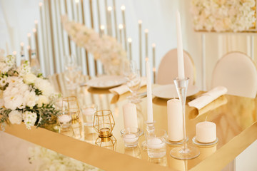 Table newlyweds in gold color. white beautiful candles and a bouquet of fresh flowers