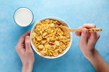 Yellow corn flakes and a glass of milk for dry healthy breakfast. Top view. Cereals spoon and bowl...