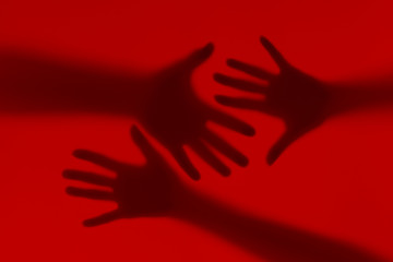 Silhouette of male and female hands on a red background.