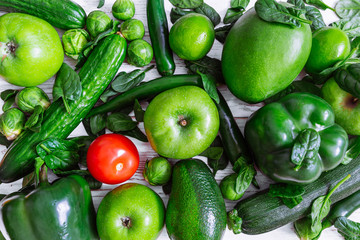 be different concept. red tomato surrounded by green fruits and vegetables. overhead view