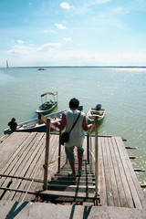 View of a man walking down the jetty stairs and a man tie a rope to secure his boat to a wooden jetty. view from a wooden jetty
