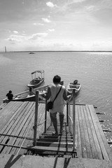 View of a man walking down the jetty stairs and a man tie a rope to secure his boat to a wooden jetty. view from a wooden jetty