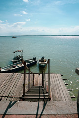 View of a man by the jetty securing rope from his boat to a wooden jetty. view from a wooden jetty