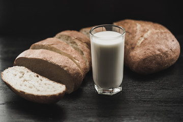 Ciabatta and a glass of milk on a wooden background.