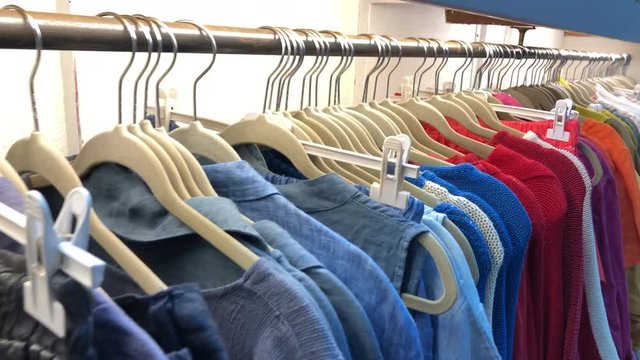 Row of colorful apparel on shoulder hangers. Wardrobe showcas
