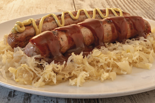 wurstel e crauti nel piatto con salsa barbecue e senape ddi fronte altra posa