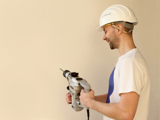 A man in a white helmet is wearing a white T-shirt for a white background with a tool in his hands close-up.