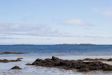 Serene Blue Ocean Scene with Rocks and Sand Low Tide