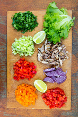 Chopped fresh vegetables with lime and beef on rustic wooden board. Tacos ingredients. Top view. From above. Flat lay, overhead.