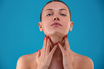 Beautiful woman with dark hair touches the neck with her hands.