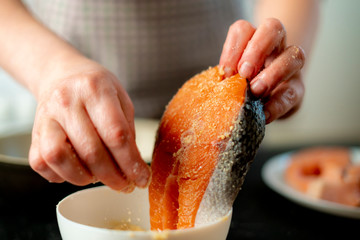 womans hands breading fish at the kitchen