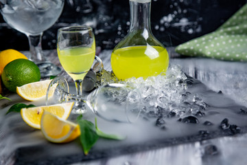 Italian typical digestive limoncello with fresh lemons in smoke, selective focus