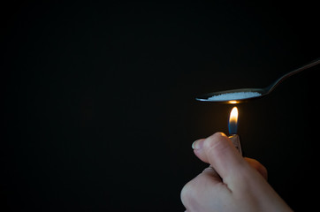woman use fire and spoon for boiling water and narcotic, cocaine, heroin or methamphetamine. She is...