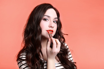 Young woman with lipstick on living coral background
