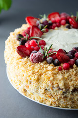Homemade sponge cake with cream and fresh berries. Carrot and orange cake, decorated with berry. Close up sweet dessert. Whole deliciouse cake. Gray background.