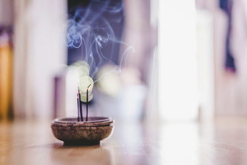 Smoking and smelling joss sticks at home, feng shui; Copy space - obrazy, fototapety, plakaty