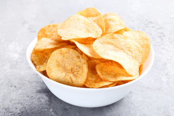 Potato chips in bowl on grey wooden table