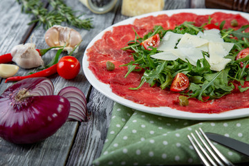 close-up carpaccio meat with arugula and slices of parmesan cheese