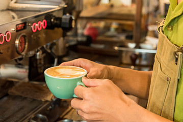 Barista cafe making a cup of coffee latte art in coffee shop