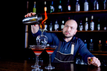 Fiery show at the bar. The bartender makes hot alcoholic cocktail and ignites bar. Bartender prepares a fiery cocktail. Fire on bar.