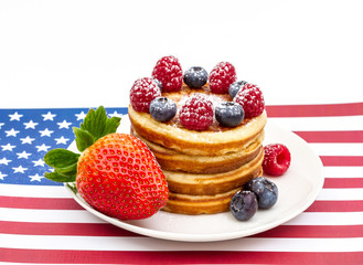 Heap of pancakes with berries on USA flag
