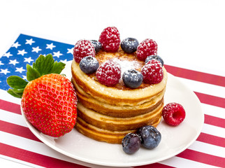 Heap of pancakes with berries on USA flag