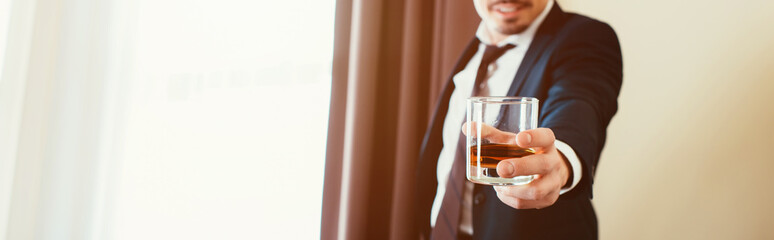 cropped view of businessman in formal wear holding glass of whiskey in hotel room