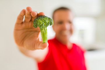 Fototapeta na wymiar MIiddle age man showing piece of broccoli