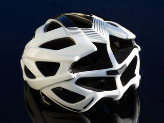 White bicycle helmet on a black table. Rear side view.