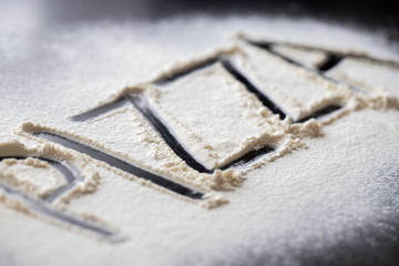 Pizza word written in flour on black table