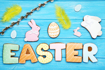Easter gingerbread cookies with yellow feathers and willow branch on wooden table